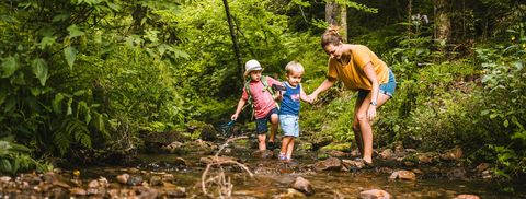 Frau mit Kindern am Fluß im Wald